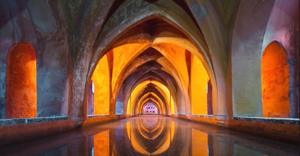 inside a temple water is reflecting arches of golden light